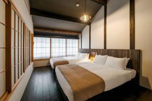 une chambre avec deux lits et une grande fenêtre dans l'établissement Izuki Machiya House, à Nishi-kujō-Toriiguchichō