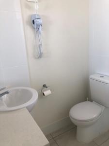 a bathroom with a toilet and a sink and a phone at Superior Studio 20 Endeavour Inn in Emu Park