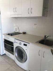a kitchen with a washing machine and a sink at Superior Studio 20 Endeavour Inn in Emu Park