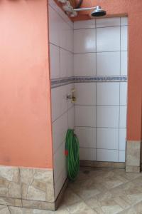 a shower stall with a green hose in a room at Casa da Fran in Maresias