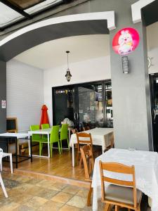 a restaurant with white tables and green chairs at Rabbitel Phuket in Phuket Town