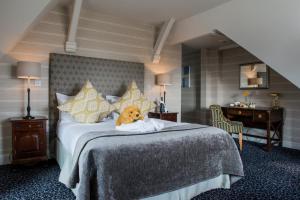 a teddy bear sitting on a bed in a hotel room at The Coed-Y-Mwstwr Hotel in Bridgend