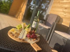 a plate of fruit and a bottle of wine on a table at Fecske Kabin in Szólád