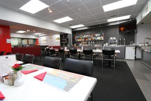 a dining room with tables and chairs and a kitchen at President Hotel Auckland in Auckland