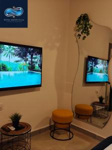 a waiting room with two stools and a flat screen tv at Royal Water Villa in Kiryat Ekron