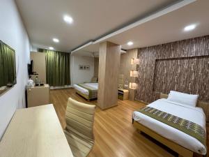 ein Hotelzimmer mit zwei Betten und einem Tisch und einem Bett in der Unterkunft Heritage Residency By Lemongrove Hospitality in Madurai