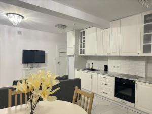 a kitchen with white cabinets and a table with flowers at Apartament Grójec in Grójec