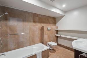 a bathroom with a tub and a toilet and a sink at Walter Peak View Apartment in Queenstown