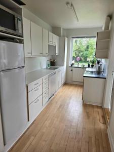 a kitchen with white cabinets and a wooden floor at Cozy Townhouse Near Beach, Harbor, And Lalandia in Rødby