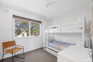 a white bedroom with a bunk bed and a window at Cowes On Hill in Cowes