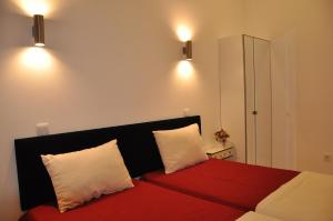 1 dormitorio con 1 cama roja y blanca con 2 almohadas en Clerigos-H, en Oporto