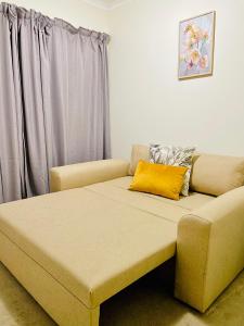 a couch with a yellow pillow on top of it at The Classy West End 1 bed with sleeper couch in Midrand