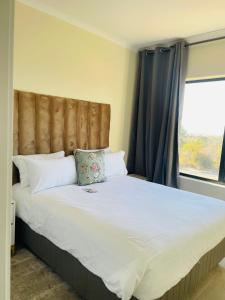 a bedroom with a large bed with a large window at The Classy West End 1 bed with sleeper couch in Midrand