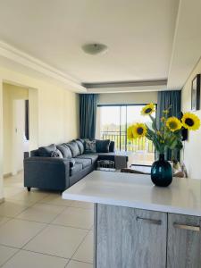 a living room with a couch and a vase of flowers at The Classy West End 1 bed with sleeper couch in Midrand