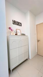 a white cabinet in a white room with flowers on it at Inara Homestay in Kuala Lumpur