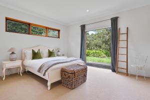 a white bedroom with a bed and a large window at The Bundanoon Lakehouse in Bundanoon