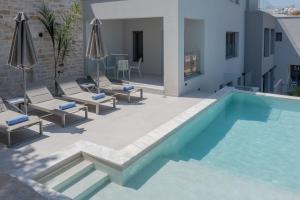 a swimming pool with chaise lounges and chairs next to a building at ArtCotel Luxury Villa in Rethymno Town