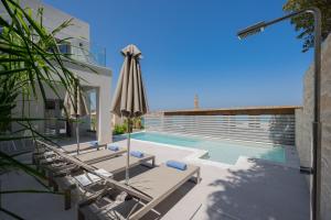 a pool with chairs and an umbrella next to a house at ArtCotel Luxury Villa in Rethymno Town