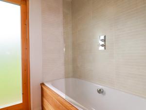 a bath tub in a bathroom with white tiles at 1 Hedgerows in Looe +41 photos