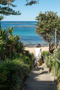 Una mujer caminando por un camino a la playa en House of Banksia, en Long Jetty