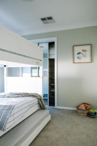 Un dormitorio blanco con una cama y un espejo. en House of Banksia, en Long Jetty
