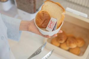 a person holding a loaf of bread in a container at No25 Hotel Jeonju Sanjeong in Jeonju