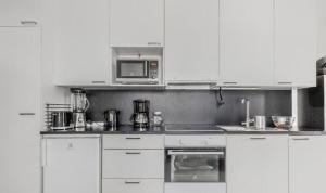 a kitchen with white cabinets and a microwave at Cozy and modern apartment in Luoma