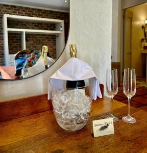 a table with two wine glasses and a mirror at De Zeven Guest Lodge in Stellenbosch