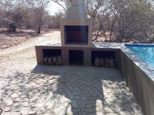 a fireplace on a stone path next to a pool at Le Lion Dort in Marloth Park +9 photos