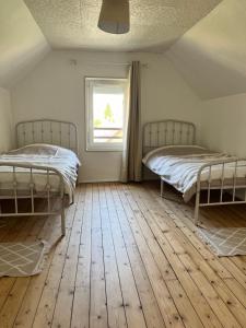 two beds in a room with a window and wooden floors at Maison de ville - 7 couchages in Saint-Pierre-le-Moûtier