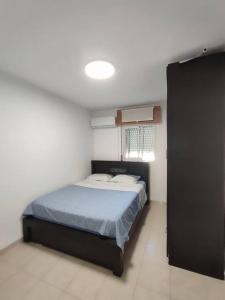 a bedroom with a bed with a blue comforter at Home with a balcony by the sea 60-5 in Qiryat H̱ayyim