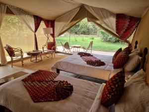 a bedroom with two beds and a tent with a table and chairs at Dolly Farm & River Camp, Luxury Tents in Usa River