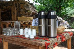 a table with two thermos and cups on it at Dolly Farm & River Camp, Luxury Tents in Usa River