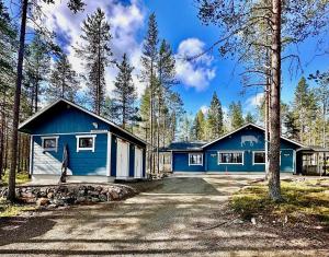 a blue house in the middle of a forest at Hippu Holiday Home in peaceful location near Äkäslompolo in Äkäslompolo