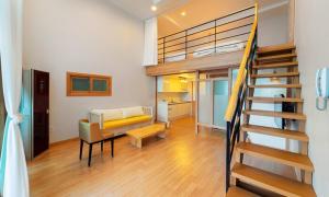 Habitación con escalera y sala de estar con sofá. en Geojae Mins Pension, en Geoje