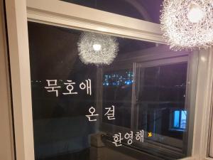 a window with two chandeliers and writing on it at Donghae Mookhoae Pension in Mukho-dong