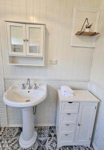 a white bathroom with a sink and a cabinet at Old Oak Tree Cottage in Rydal +42 photos