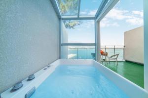 a large bath tub in a room with a large window at Geoje Theview Kids Poolvilla in Geoje