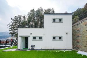 a white house with a green lawn in front of it at GaPY Mom Stay Private Pool Villa in Gapyeong