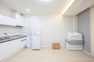 a white kitchen with a refrigerator and a sink at Yangyang Hajodae Sungsim Pension in Ka-kōtei-ri