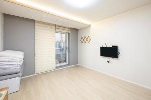 a room with a bed and a tv on a wall at Yangyang Hajodae Sungsim Pension in Yangyang