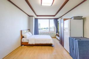 a bedroom with a bed and a refrigerator and a window at Yangyang Hajodae Condotel in Yangyang