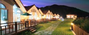 a group of buildings with tables and umbrellas at night at Hongcheon Star n Sharp Pension in Hongcheon