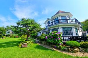 a large white house with purple flowers in the yard at Samcheok Rose Valley Pension in Samcheok