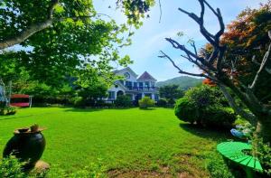 a large house with a large yard with a green lawn at Samcheok Rose Valley Pension in Samcheok