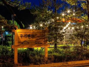 a wooden sign sitting in the grass at night at Jebudo Woori Pension in Hwaseong