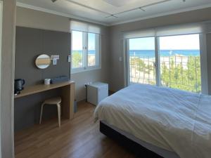 a bedroom with a bed and a desk and windows at Yangyang Happy House Pension in Ka-kōtei-ri +7 photos