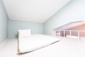 a white bedroom with a bed in a attic at Gangneung Dawon Forest Private Pension in Gangneung +10 photos