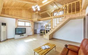 a living room with a wooden staircase and a television at Hongcheon Oz Pension in Hongcheon