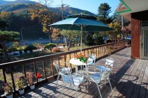 a table and chairs with an umbrella on a balcony at Jeongseon Villa in Jeongseon